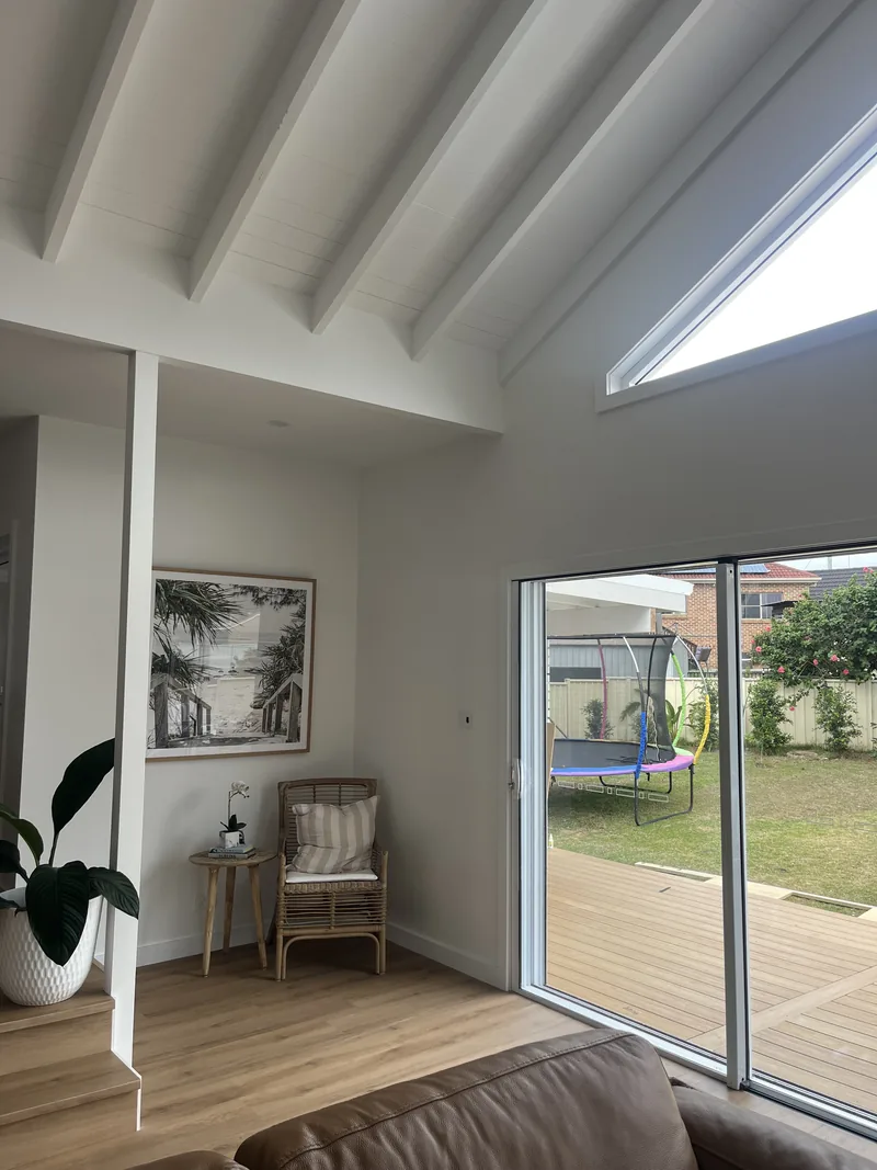 Corner of a living room with a sliding glass door open to a lawn and a trampoline