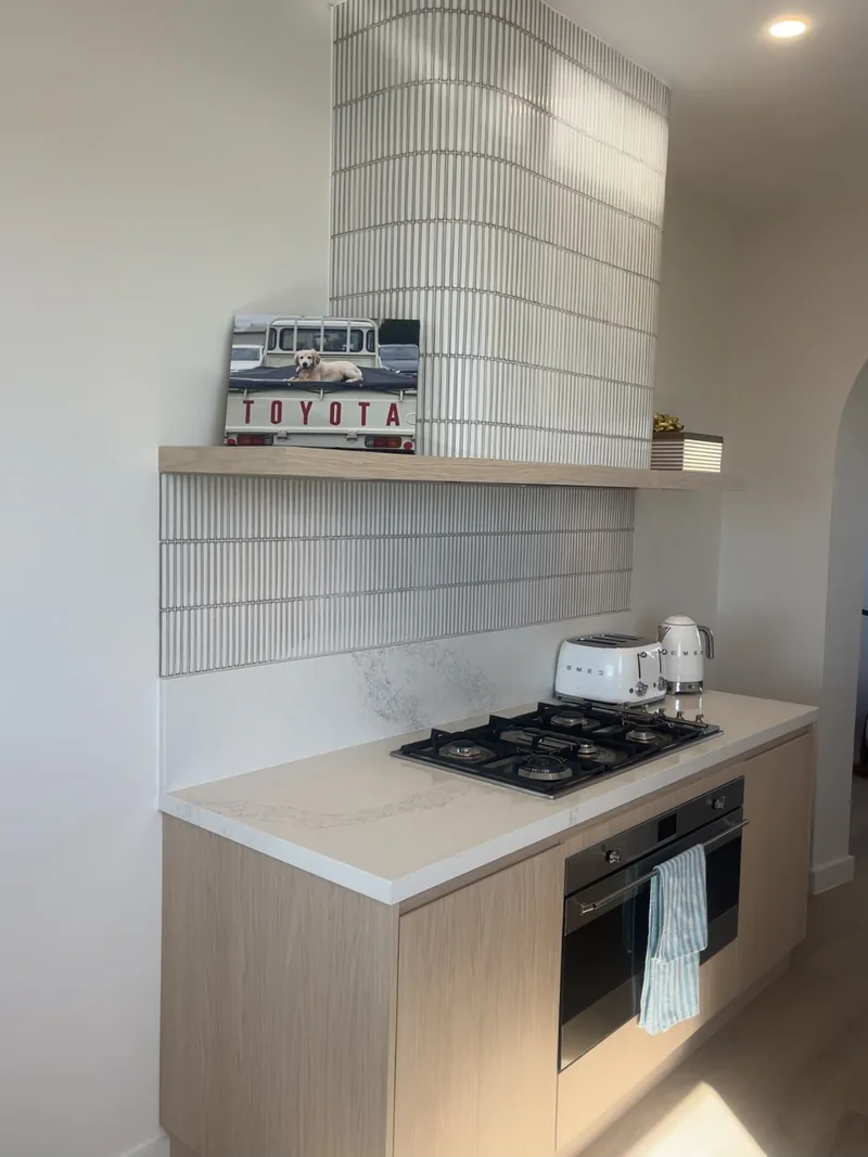 Kitchen with a fluted-tile rangehood surround, a stone-look benchtop, a gas cooktop and timber-look cabinets